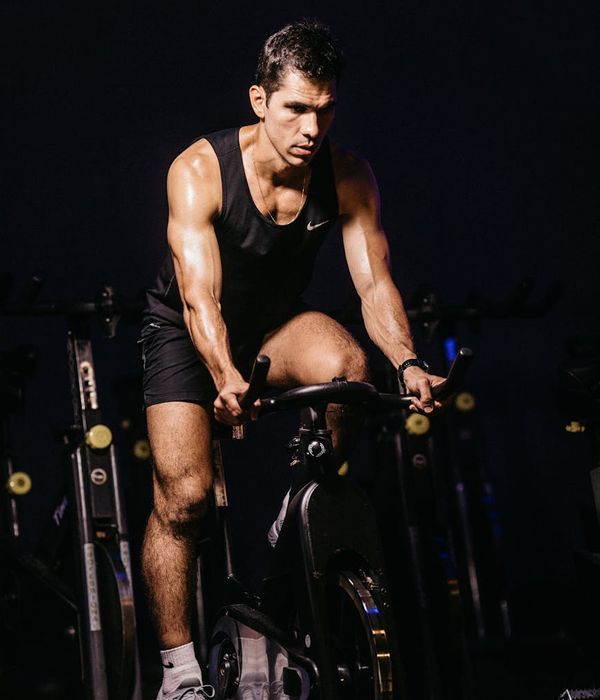 Man in a focused stance performing a strength exercise in a dark gym.